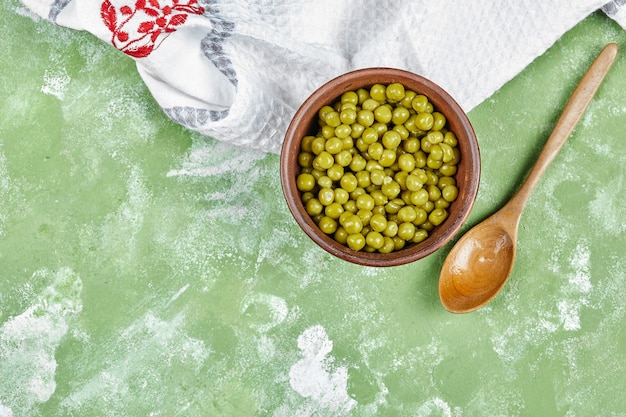 Free Photo a bowl of boiled green peas with a wooden spoon and a tablecloth