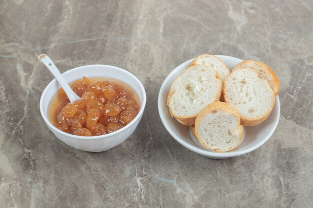 Bowl of bread slices and berry jam on marble. High quality photo