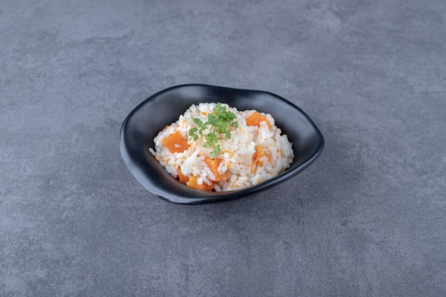 A bowl of carrot rice , on the marble surface.