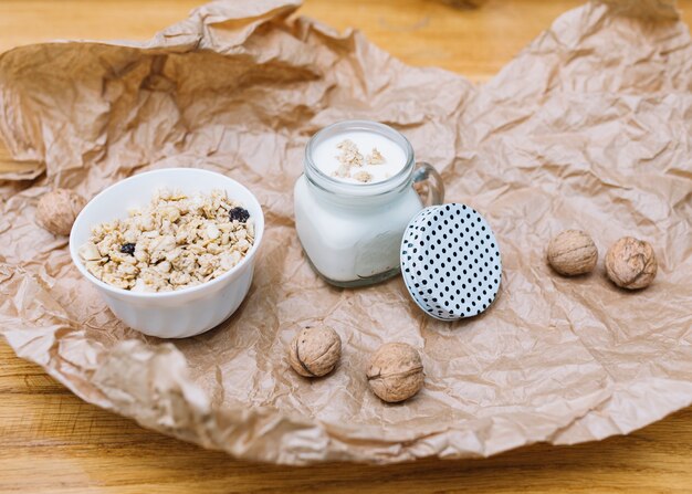 Bowl of cereals; milk and walnuts on crumbled brown paper