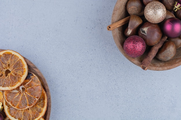 Free photo bowl of chestnuts with baubles and dried oranges.