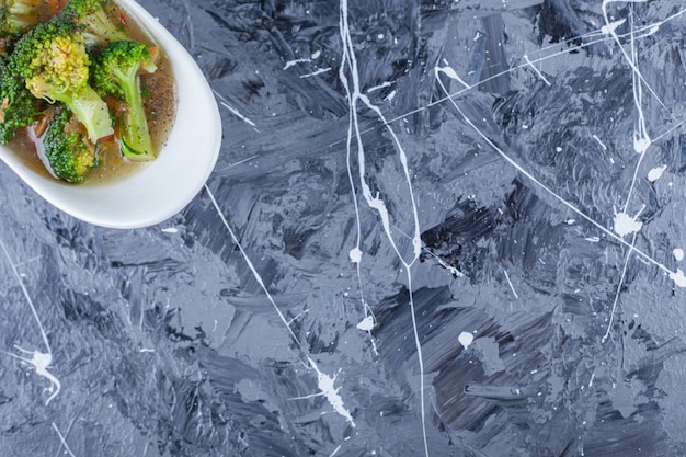 Free Photo bowl of chicken soup and vegetables on a trivet, on the blue table.