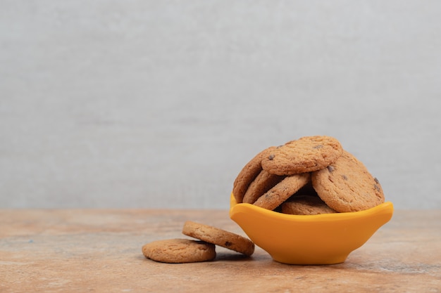 Bowl of chocolate chips cookies on marble background.