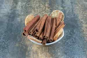 Free photo bowl of cinnamon sticks on marble table.