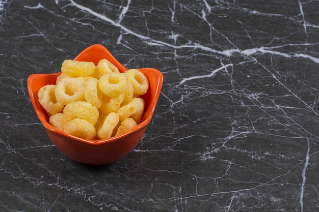 A bowl of corn rings, on the marble surface