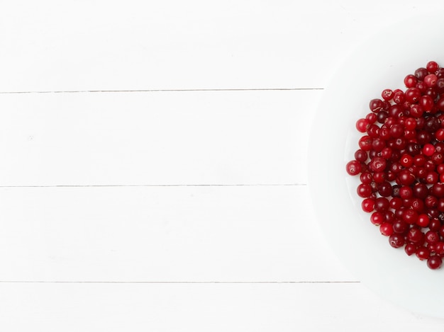 Free photo bowl of cowberries on old wooden table