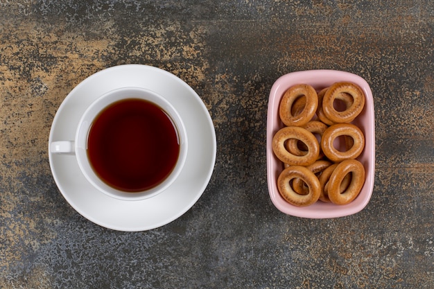 Bowl of crackers and cup of tea on marble.