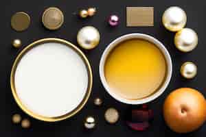 Free photo a bowl of cream with a golden lid sits on a black background with christmas decorations.