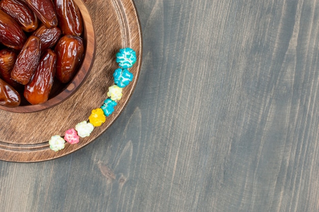 Free photo bowl of dates and popcorns on wooden plate