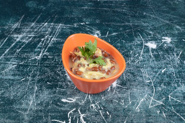 Bowl of delicious soup with pasta and beans on blue background. High quality photo