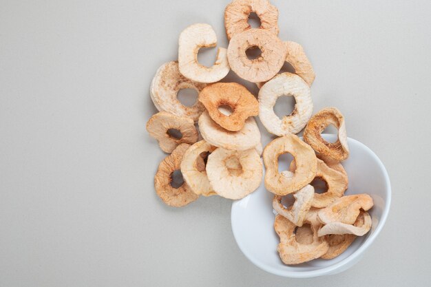 Bowl of dried apple rings on white surface