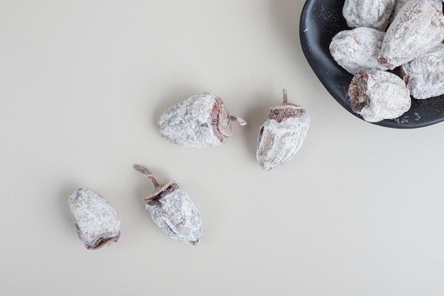 Free photo bowl of dried persimmon on beige surface