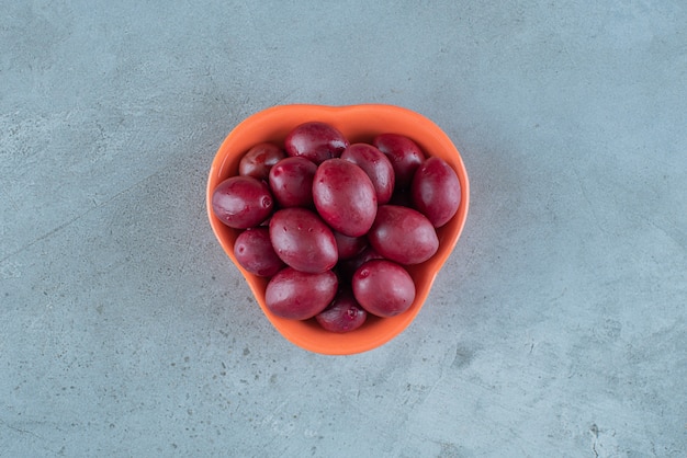 Free Photo a bowl of fermented plums on the marble surface