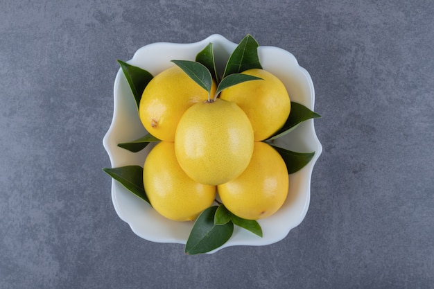 Free photo bowl of fresh lemons on grey background.