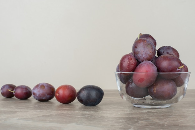 Bowl of fresh plums on marble table.