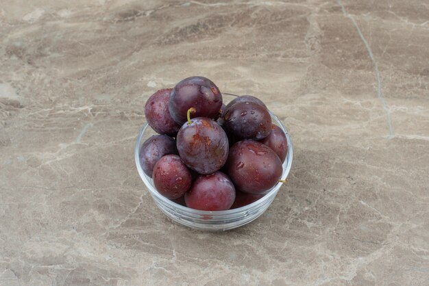 Bowl of fresh plums on marble.