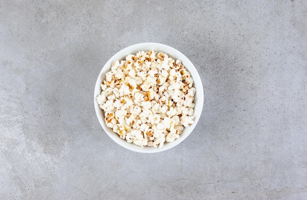 A bowl of freshly cooked popcorn on marble surface