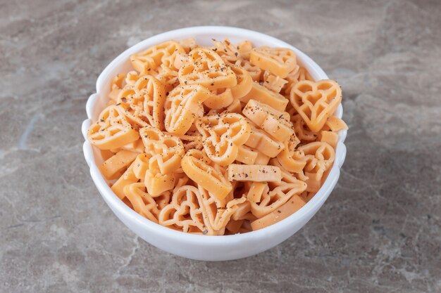 Bowl full of different shaped pasta , on the marble.