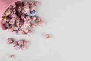 Free photo bowl full of purple popcorn fallen over on a folded towel, on marble table.