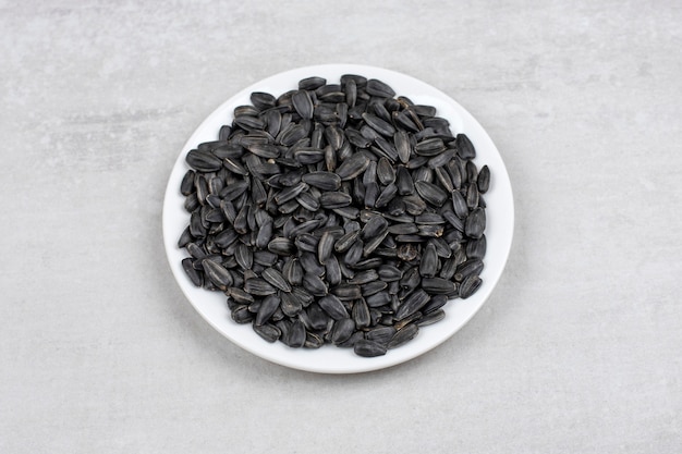 Bowl full of sunflower black seeds placed on stone table . 