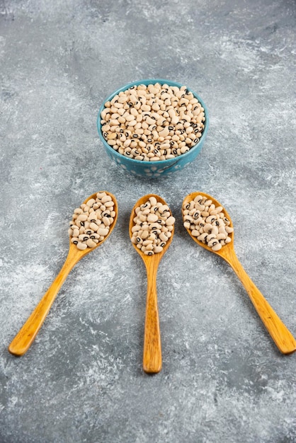 A bowl full of white raw kidney beans with wooden spoons.