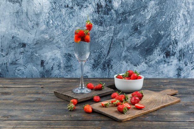 Free Photo bowl, glass and cutting board with strawberries