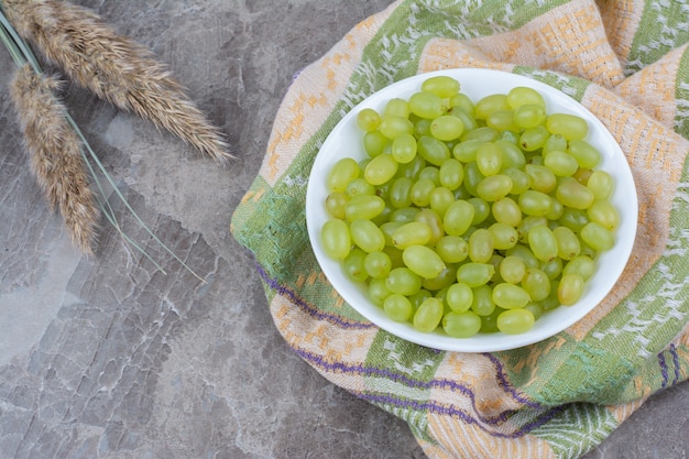 Bowl of green grapes on colorful tablecloth. 