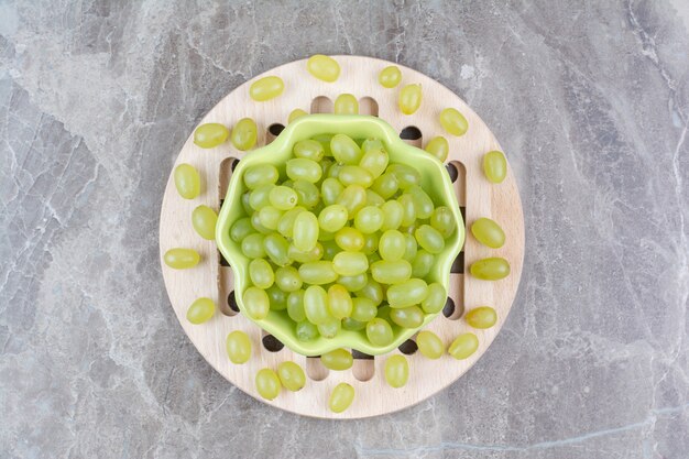 Bowl of green grapes on wood piece. 