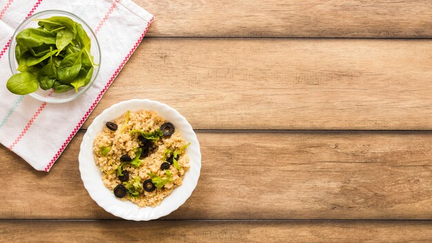 Bowl of healthy oats garnished with basil leaf and olive for breakfast