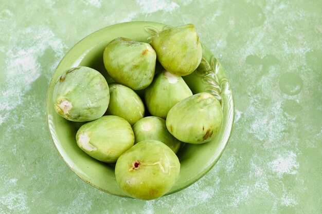 A bowl of juicy green figs on green.