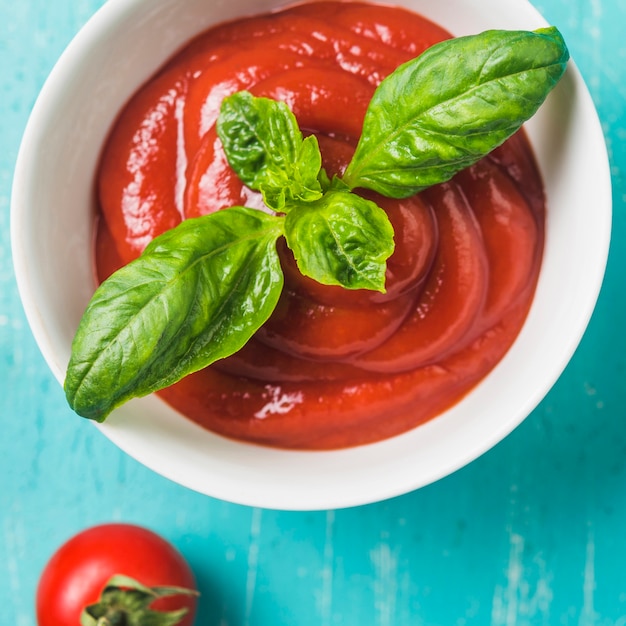 Free Photo bowl of ketchup and basil on turquoise background