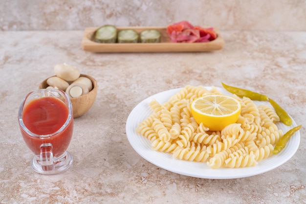 Bowl of mushrooms, appetizer tray of pickles, main course of macaroni and dressing of ketchup on marble surface.