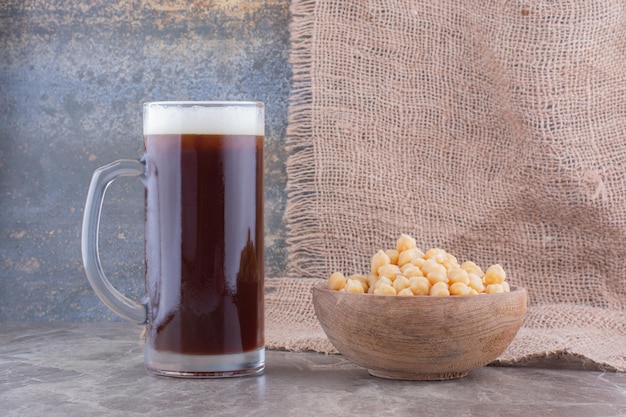 Bowl of peas and glass of dark beer on marble table. High quality photo