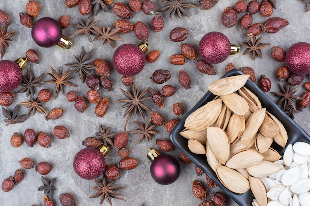 Bowl of pistachio and pumpkin seeds with rosehips and Christmas balls. 