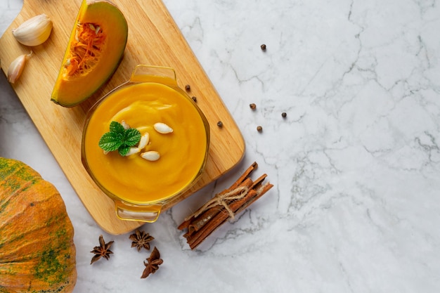 Bowl of pumpkin soup place on wooden cutting board