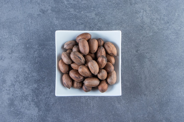 A bowl of raw nuts , on the marble background.