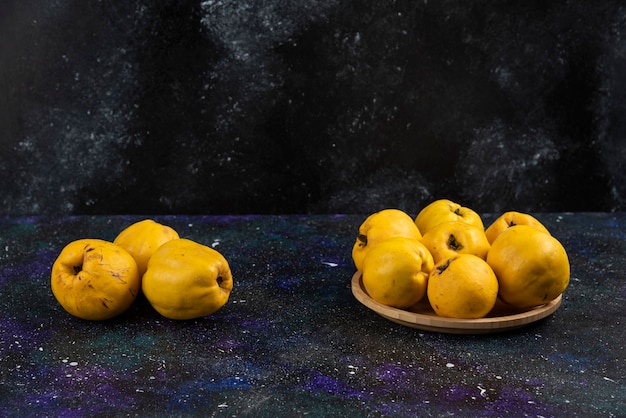 Free photo bowl of ripe quince fruits placed on dark table.