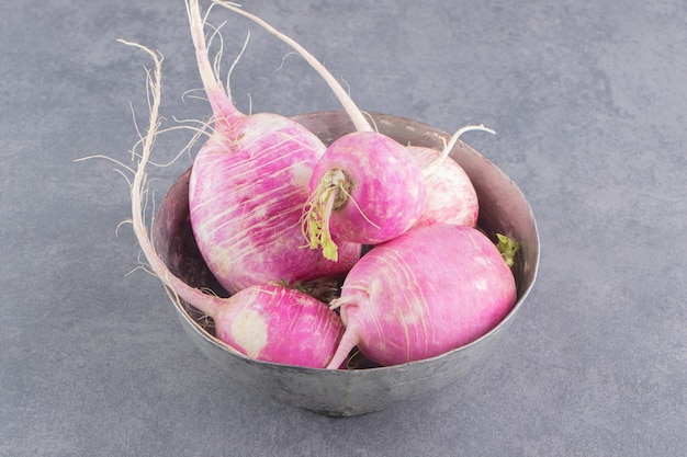 A bowl of ripe radishes on the marble surface