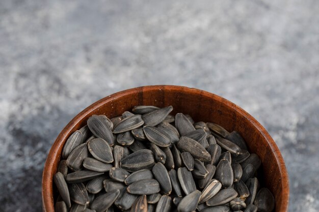 Bowl of roasted black sunflower seeds on white surface