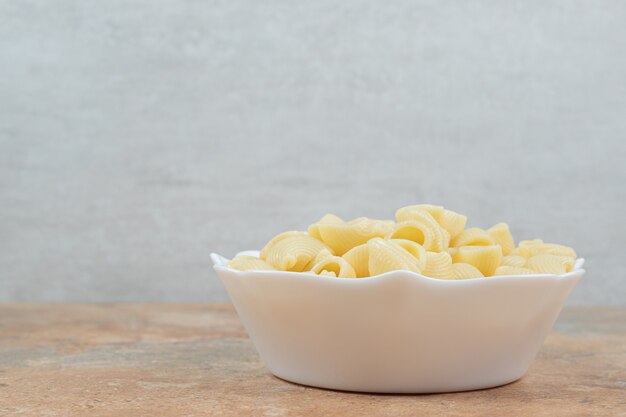 Bowl of seashell shaped pasta on marble table