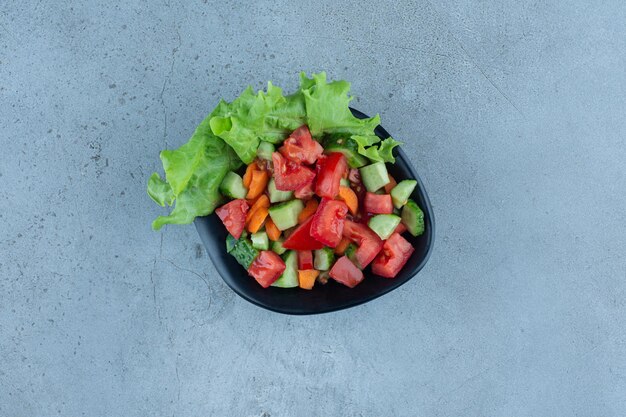 A bowl of shepherd's salad on marble surface