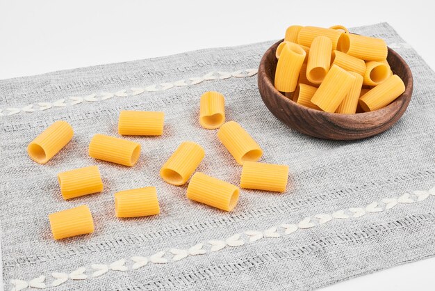 A bowl of short cut pasta on grey tablecloth. 