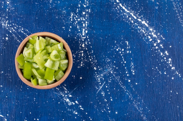 Free photo bowl of sliced green bell peppers on marble table.