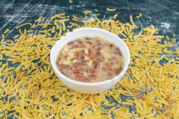 Free photo bowl of soup with beans and scattered pasta on blue background. high quality photo