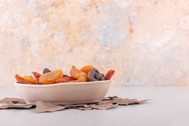 Free Photo bowl of various organic fruits with dry leaf on white background. high quality photo