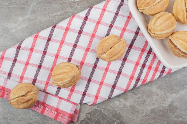 Bowl of walnut shaped cookies on tablecloth. 