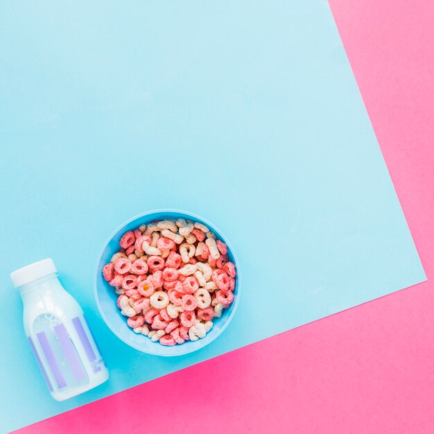 Bowl with cereals and blue milk bottle on table 