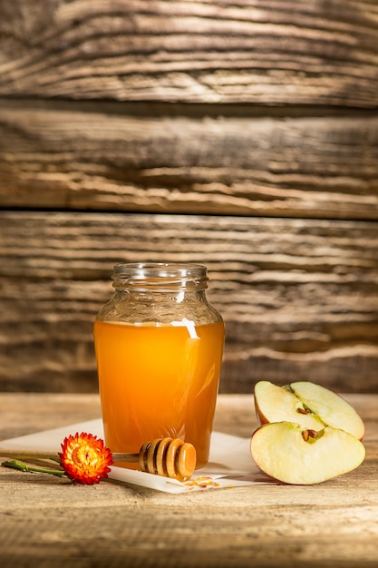 The bowl with honey on wooden table.The bank of honey stay near wooden spoon