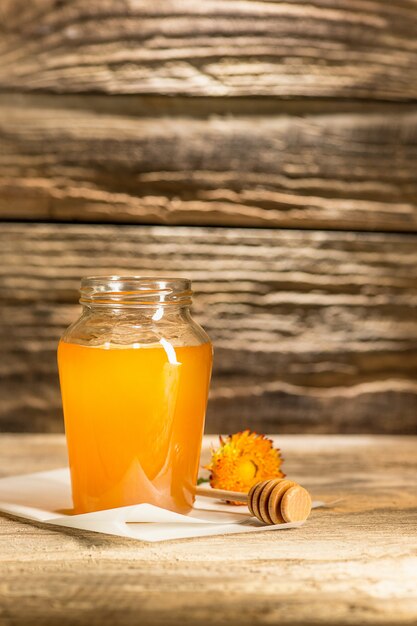 The bowl with honey on wooden table.The bank of honey stay near wooden spoon