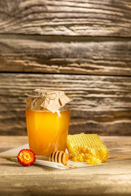 The bowl with honey on wooden table.The bank of honey stay near wooden spoon